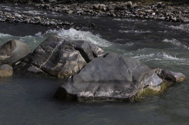 Kıyıda, arka planda, Kafkaslarda, hızlı nehir ve taş
