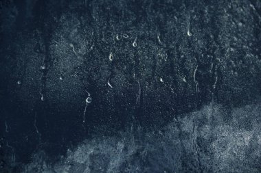 Arka planda, cam üzerinde donmuş su damlaları