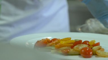 Şef beyaz üzerine sebzeli balık bir tabak pişmiş.