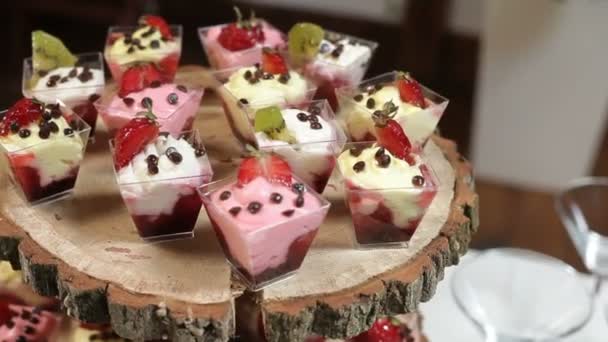 Вкусные украшенные сладости на деревянном столе, фуршет — стоковое видео