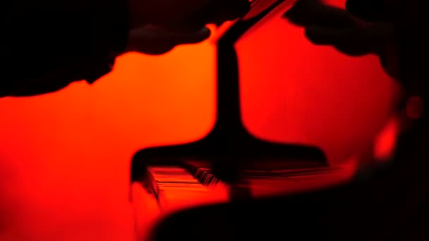 Un pianista cierra una tapa del piano, fondo rojo — Vídeos de Stock