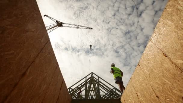 Trabajador de la construcción sosteniendo un conjunto de planes, mirando hacia arriba en las vigas del techo — Vídeos de Stock