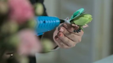 bir çiçekçi bir buket üzerinde beyaz bir kurdele tutkallar