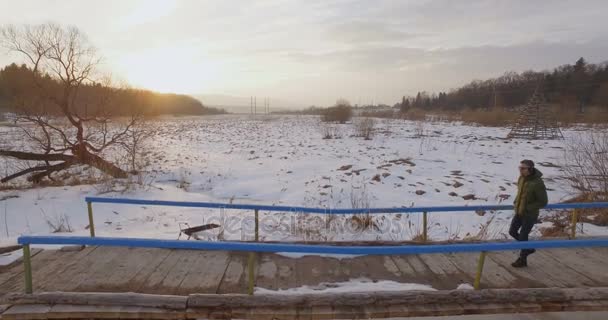 Havadan görünümü adam üzerinde köprü el yapımı günbatımı kış — Stok video