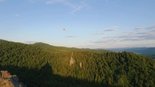 Hot Air Balloon fly through the sky in a landscape of mountains near the rocks — Stock Video