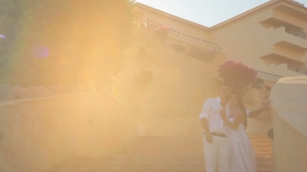 Das junge Paar läuft im weißen Kleid die Treppe hinunter, die Sonne scheint — Stockvideo