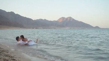 Sarılma ve öpüşme denizde yatan genç Çift
