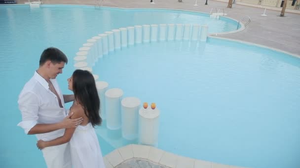 Pareja joven disfrutando de bebidas junto a la piscina fuera de la piscina moderna de lujo — Vídeo de stock