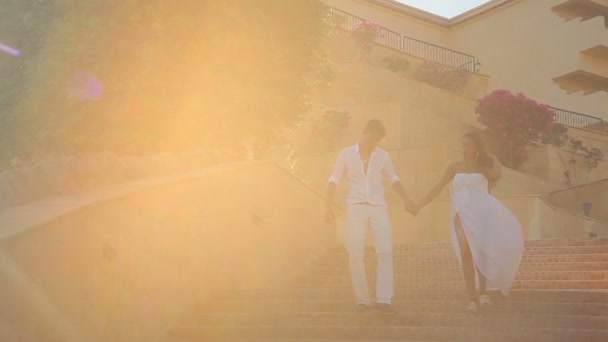 Молода пара ходить по сходах, на тлі архітектури — стокове відео