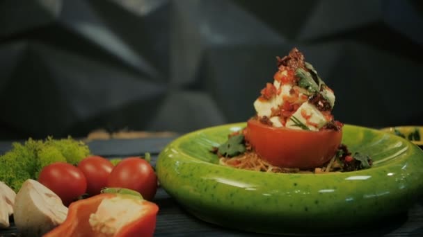 Tomates aux tomates séchées et fromage feta. Snacks froids. Sur un fond en bois noir, photo de poupée — Video