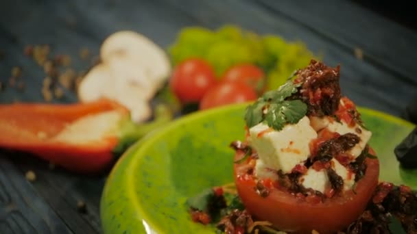 Tomaten mit getrockneten Tomaten und Feta-Käse kalte Snacks. auf schwarzem Holzgrund, Nahaufnahme — Stockvideo