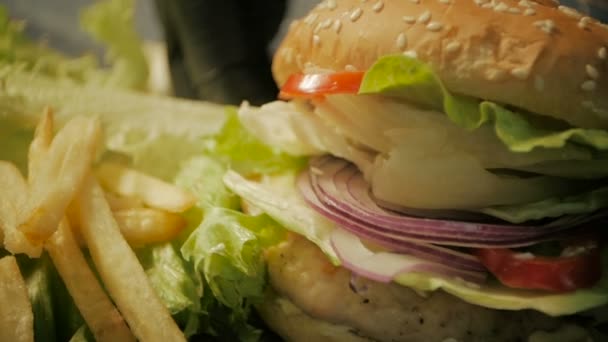 Hambúrguer Cheeseburger com carne suculenta e ingredientes de salada fresca em uma mesa de madeira rústica. de perto — Vídeo de Stock