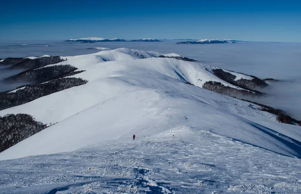 Одинокий турист поднимается на снежный горный хребет — стоковое фото