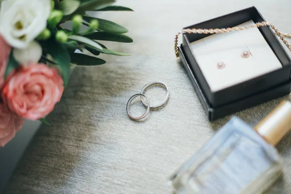 Hermosos anillos de boda se encuentran en una mesa el fondo de un ramo de flores —  Fotos de Stock