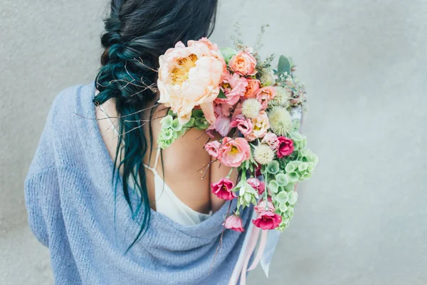 Dekoratif bir buket çiçek onun elinde tutan bir kadın