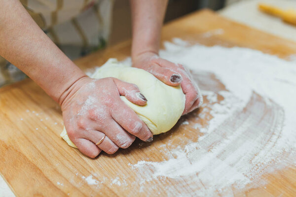 Making dough by female hands on wooden table background