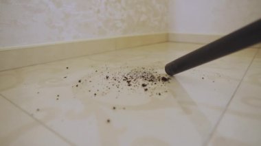 Woman using a vacuum cleaner to clean tiles in a home interior