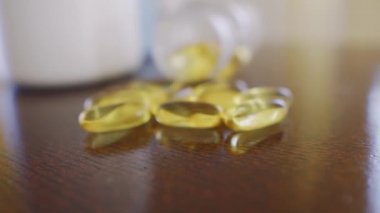 Omega 3 hapları masanın üzerinde, yavaşça şişeye yaklaşıyorlar. Makro yakın çekime odaklan.