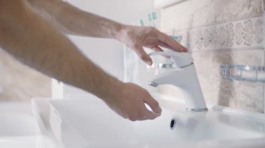 Kapat. Adam ellerini banyoda sabunsuz yıkıyor. Sabah rutin temizlik.