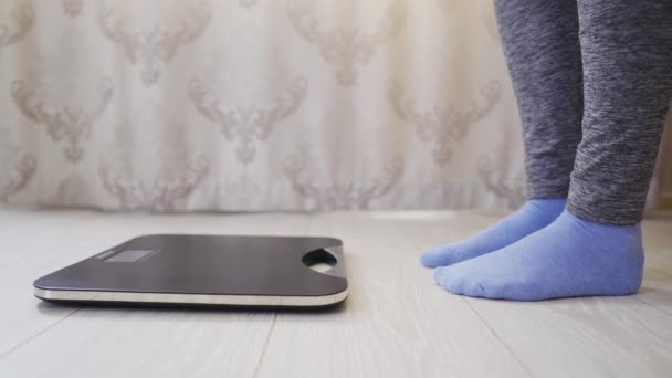 Женщина в носках и леггинсах проверяет вес на электронном весе с помощью дисплея — стоковое видео