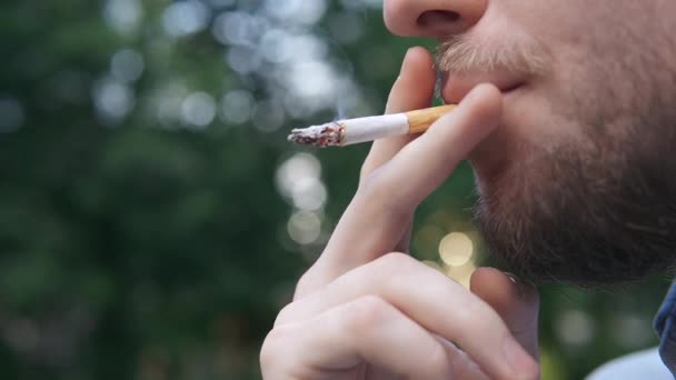 Bärtiger Mann raucht Zigarette auf Hintergrundbeleuchtung Stadt — Stockvideo