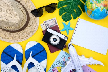 Gezgin aksesuarları, sarı arka planda tropikal palmiye yaprağı dalları ve metin için boş alan. Seyahat tatili konsepti. Yaz dönemi. Yol iskeleti hazır. Düz yatış, üst görünüm.