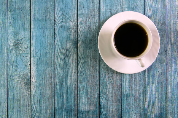 White cup with black coffee on a blue wooden background