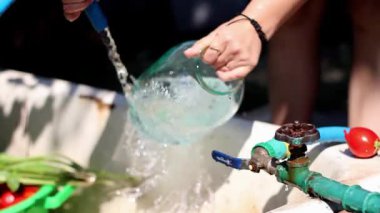 O onun elleri kavanoz ve sinek sprey su sokakta yaz aylarında güneşli bir günde yıkar