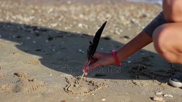 Το κορίτσι σύρει μια καρδιά από το φτερό στην άμμο στις ακτές της Αζοφικής Θάλασσας Royalty Free Βίντεο Αρχείου