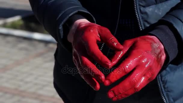 Een Man werpt zijn Hand in de verf maximaal gezicht in het Park buiten — Stockvideo