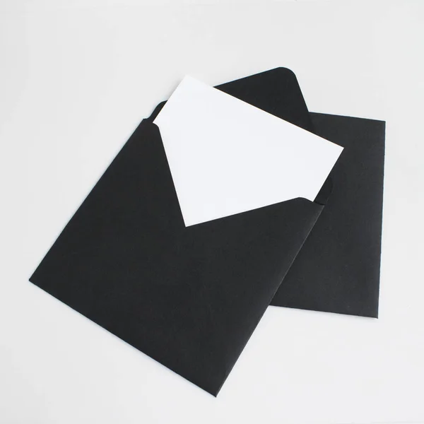 Två svarta kuvert med vitt papper på grå bakgrund. Vykortsmall. — Stockfoto