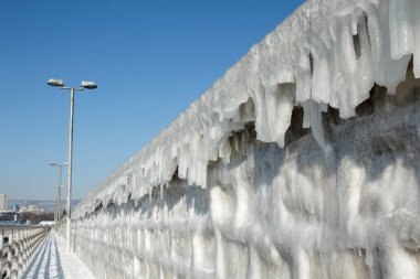 Mavi gökyüzü karşı buz sarkıtları ile dondurulmuş dalgakıran