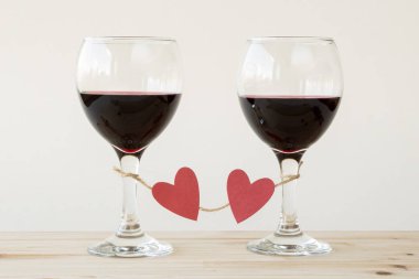 İki bardak kırmızı şarap, kırmızı kalpler ile bağlı