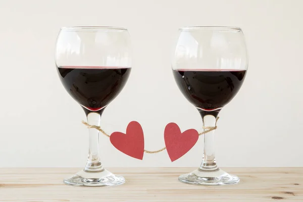 Dois copos de vinho tinto, amarrados com corações vermelhos — Fotografia de Stock