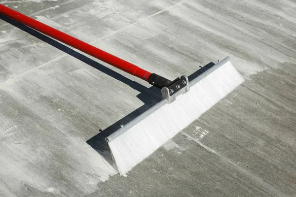 Sapu menyelesaikan beton dengan bulu plastik dan gagang merah — Stok Foto