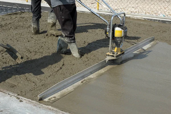 Smoothing fresh concrete with gas powered vibrating screed machine — Stock Photo, Image