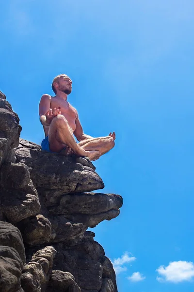 Jovem meditando sobre as rochas no topo da montanha — Fotografia de Stock