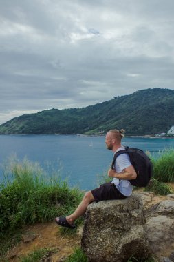 Taş üzerine oturan bir backpacker. Oturan bir kişi yan görünüm 