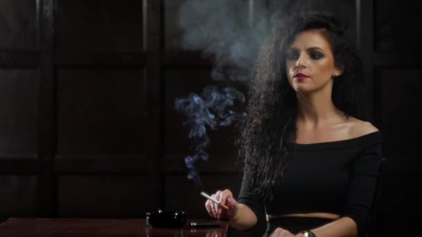 Μια νεαρή γυναίκα μελαχρινή είναι το κάπνισμα ενός τσιγάρου. — Αρχείο Βίντεο