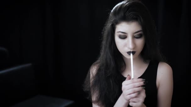 Goth girl with black eyes occasionally prefers dragging a 120mm cigarette. — Stock Video