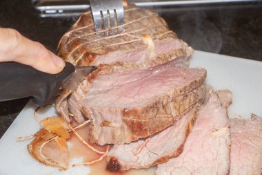 Kadın çatal ve bıçakla biftek doğruyor.