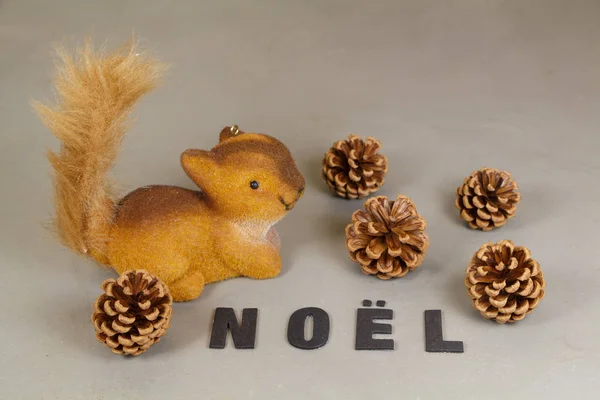 Figurka wiewiórki, szyszki sosnowe i słowo Boże Narodzenie — Zdjęcie stockowe