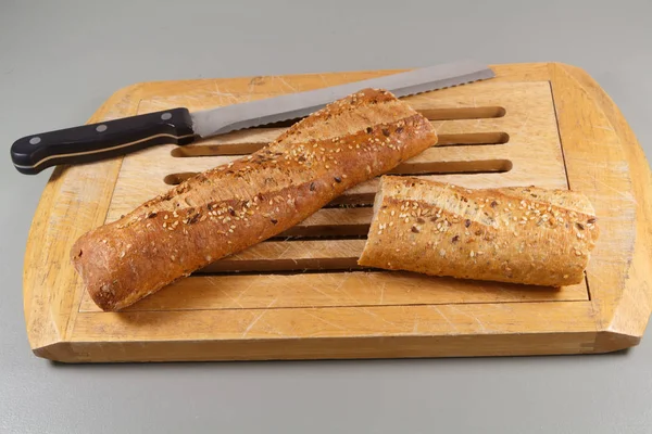 Pão de baguete e faca em uma tábua de cortar — Fotografia de Stock