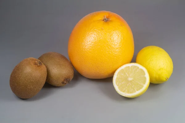 Jeruk, kiwi dan lemon pada latar belakang abu-abu — Stok Foto