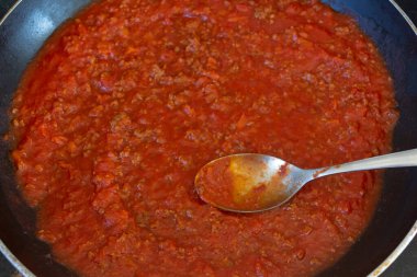 Bolonez sosu kızartma tavasında ve kaşıkta pişiyor.