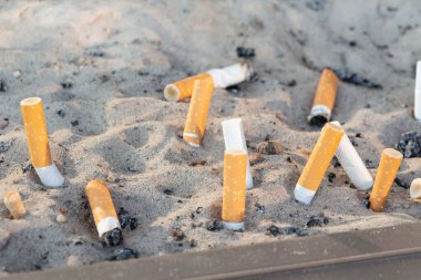 Sigara izmaritleri kül tablasında kumda.