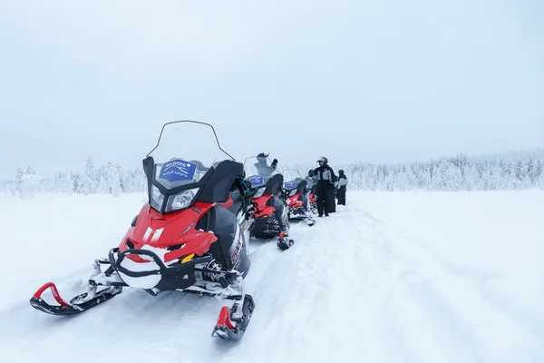 Motos de nieve con los pueblos en invierno —  Fotos de Stock
