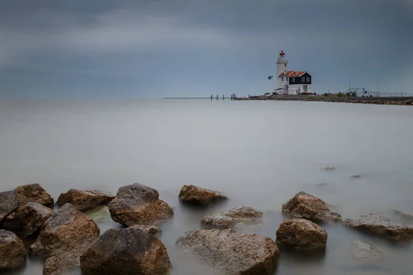 Mare nebbioso e faro sulla costa rocciosa — Foto Stock