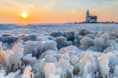 Donmuş su ve deniz feneri günbatımı uzak doğal görünümünü