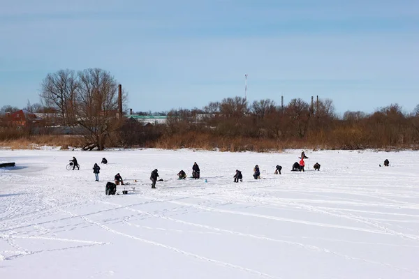 Gli abitanti delle province russe pescano sul ghiaccio di un piccolo fiume ghiacciato in inverno . — Foto Stock